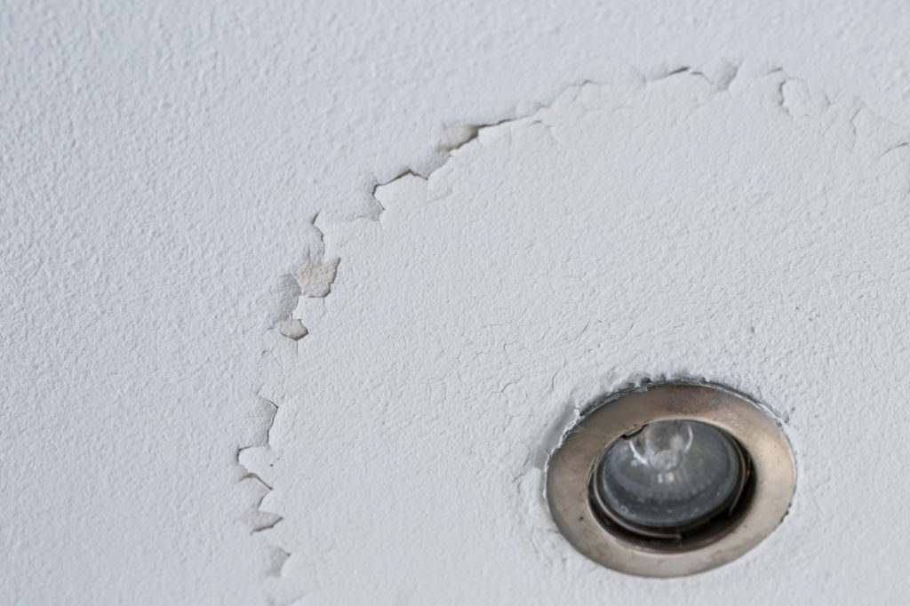 Flaking paint around a ceiling light fixture